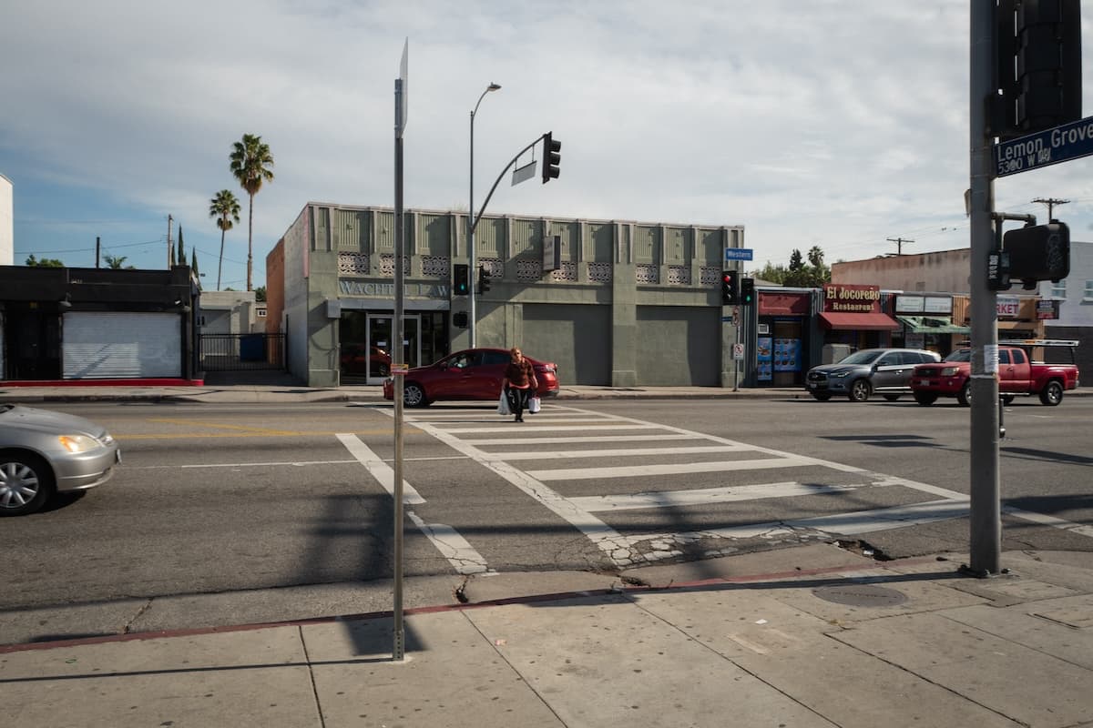 Western street with person crossing and some cars waiting to drive through